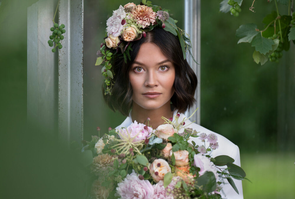 Close-up of a bride, wearing flowers on her head and a bouquet in her hands